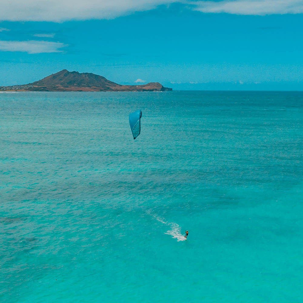 Kitesurfing in Tanzania, one kiter with blue kite against a tourquise bay